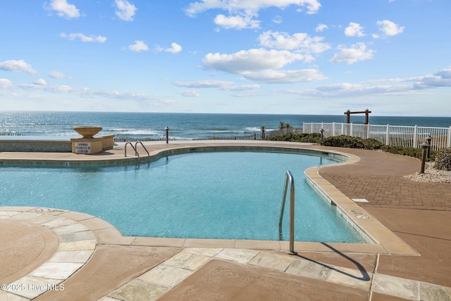 community pool featuring a patio area, a water view, and fence