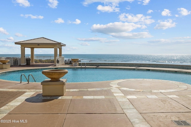 pool featuring a gazebo, a patio, a water view, and fence