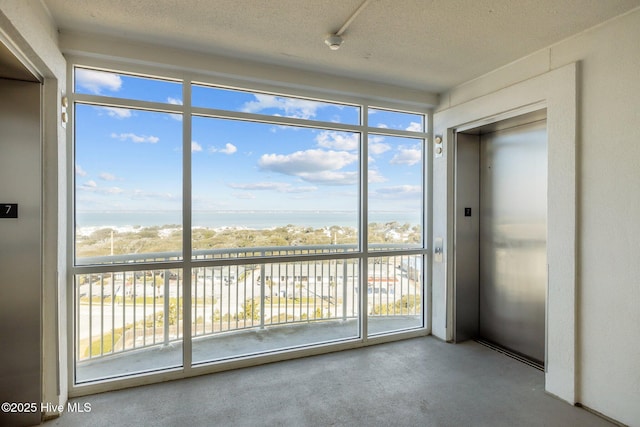 empty room with elevator and a textured ceiling