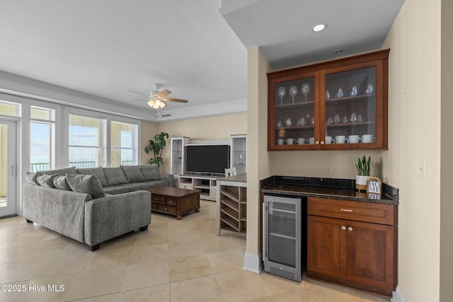 bar featuring a dry bar, light tile patterned floors, beverage cooler, a ceiling fan, and ornamental molding