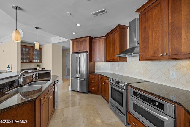 kitchen featuring stainless steel appliances, visible vents, a sink, wall chimney range hood, and dark stone counters