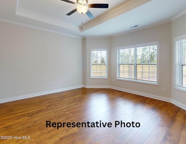 unfurnished room featuring hardwood / wood-style flooring, plenty of natural light, a tray ceiling, and crown molding