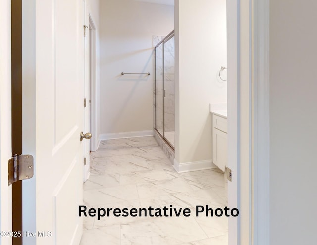 full bathroom featuring marble finish floor, a shower stall, vanity, and baseboards