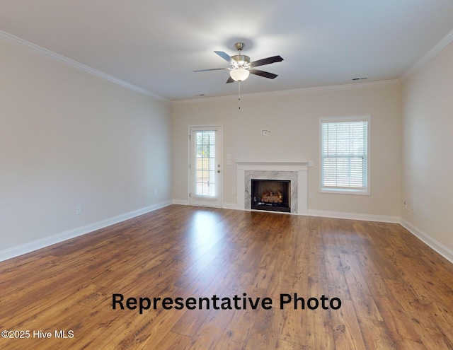 unfurnished living room with ornamental molding, visible vents, a premium fireplace, and hardwood / wood-style flooring