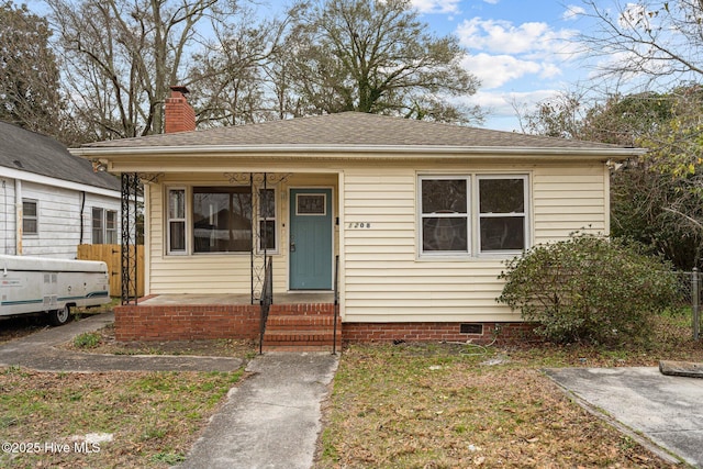 bungalow-style house featuring covered porch, a shingled roof, crawl space, and a chimney