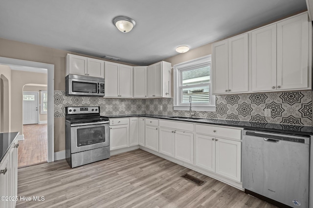 kitchen featuring stainless steel appliances, dark countertops, a sink, and visible vents