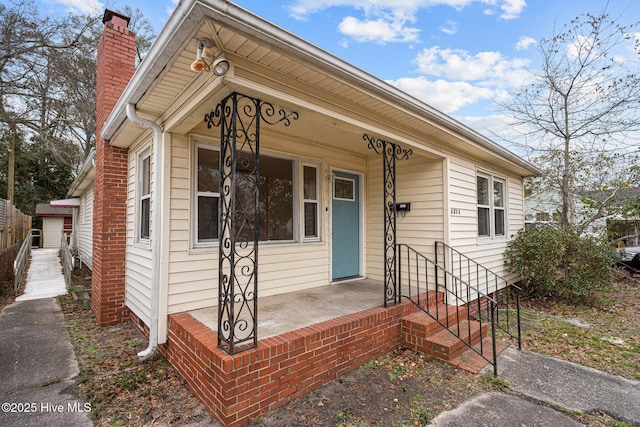 view of front of home with a chimney and a porch