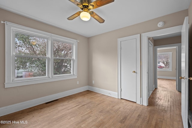 unfurnished bedroom featuring light wood-type flooring, visible vents, ceiling fan, and baseboards