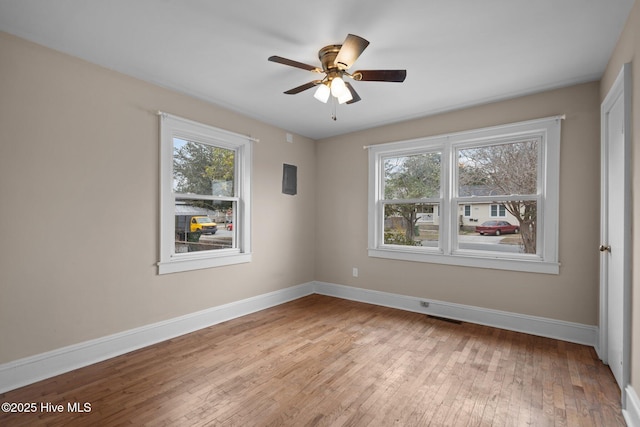 spare room with light wood finished floors, plenty of natural light, and baseboards