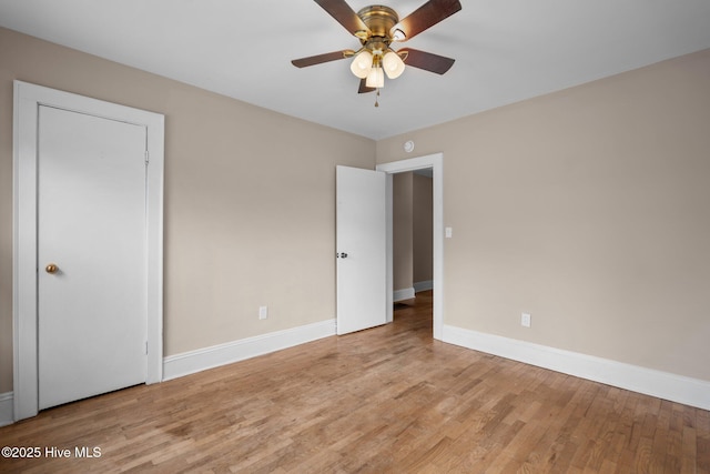 empty room featuring ceiling fan, baseboards, and wood finished floors