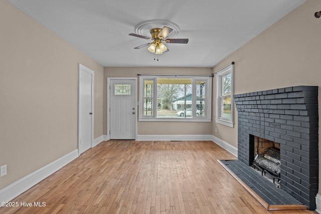 unfurnished living room with ceiling fan, a fireplace, baseboards, and wood finished floors