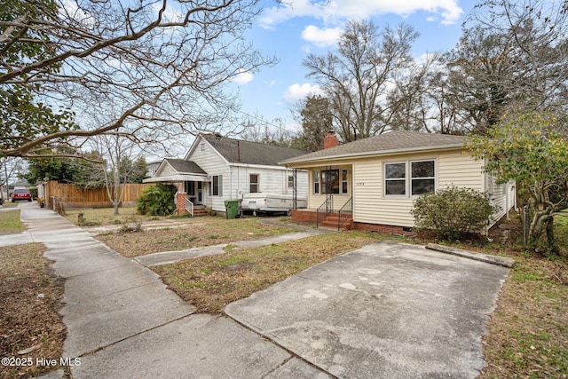 view of front of house featuring entry steps, a shingled roof, fence, crawl space, and a chimney