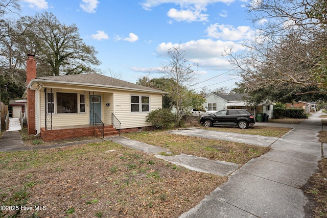 bungalow-style home with crawl space, roof with shingles, and a chimney