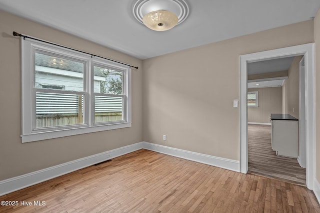 spare room featuring baseboards and wood finished floors