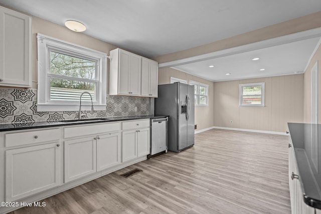 kitchen featuring visible vents, dark countertops, stainless steel appliances, light wood-type flooring, and a sink