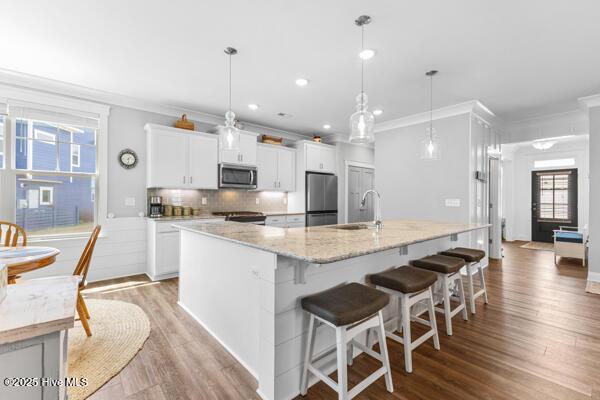 172 Everett Park Trl, Holly Ridge, NC 28445 - kitchen with stainless steel appliances, ornamental molding, a sink, white cabinetry, and a large island with sink