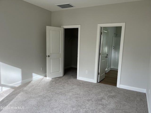 unfurnished bedroom with baseboards, visible vents, a walk in closet, carpet floors, and a closet