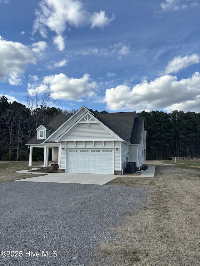 view of front facade featuring a garage, driveway, central AC unit, and a shingled roof