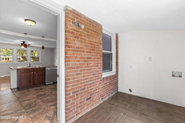 interior space featuring brick wall, a sink, a ceiling fan, stainless steel dishwasher, and wood tiled floor