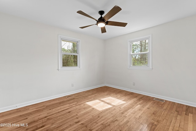 empty room featuring a wealth of natural light, baseboards, and light wood finished floors