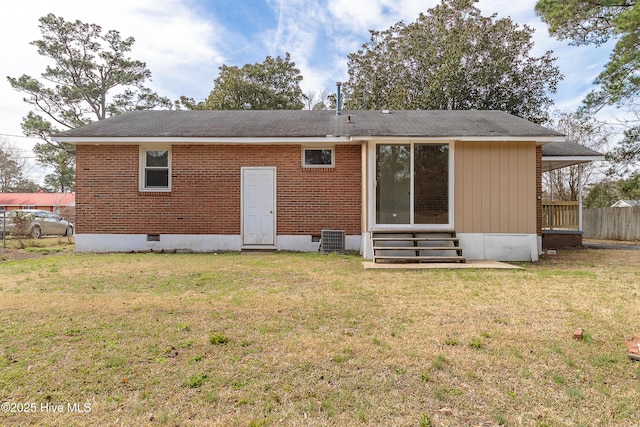 back of house featuring entry steps, crawl space, a lawn, and brick siding