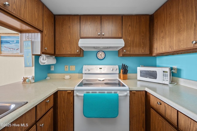 kitchen featuring light countertops, white appliances, brown cabinets, and under cabinet range hood