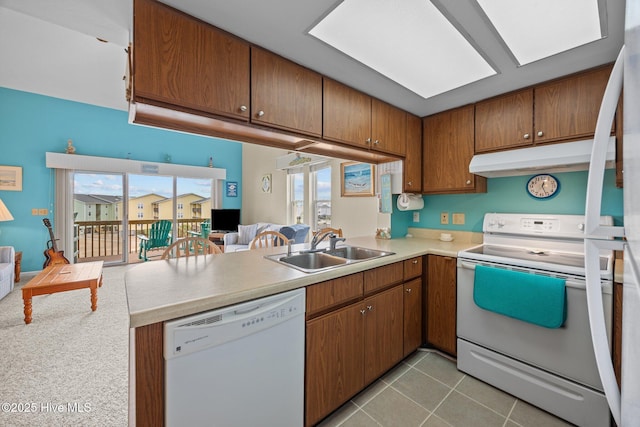 kitchen featuring white appliances, a healthy amount of sunlight, a sink, and light tile patterned floors