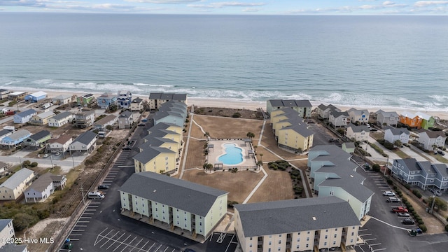 drone / aerial view featuring a water view, a residential view, and a beach view