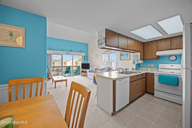 kitchen featuring white appliances, open floor plan, light countertops, under cabinet range hood, and a sink