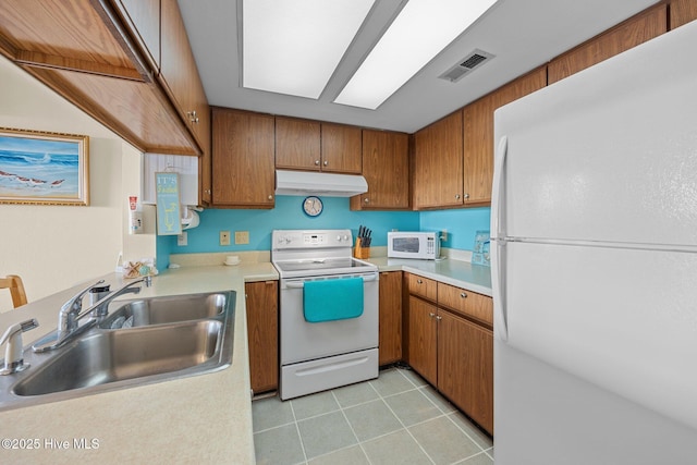 kitchen with under cabinet range hood, white appliances, a sink, visible vents, and light countertops