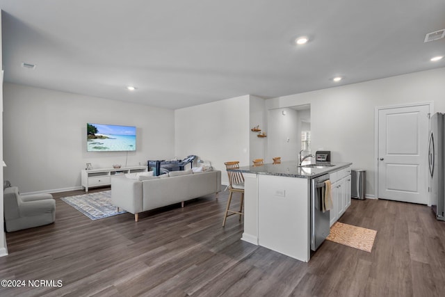 kitchen with appliances with stainless steel finishes, open floor plan, a sink, and dark stone counters