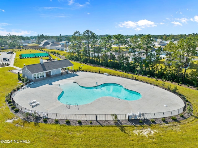 pool with a patio area, fence, and a yard