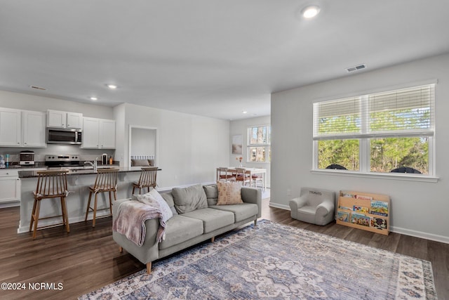 living room featuring dark wood-style floors, baseboards, and visible vents