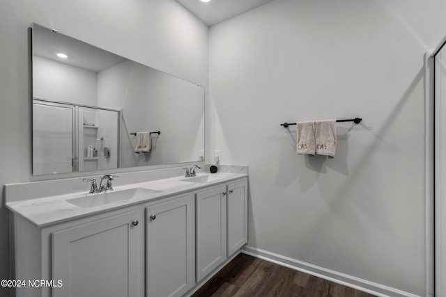 bathroom featuring a shower with door, a sink, baseboards, and wood finished floors