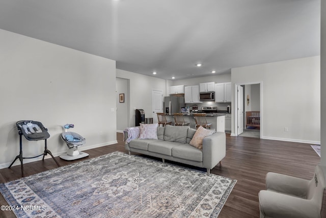 living area with baseboards, dark wood-style flooring, and recessed lighting