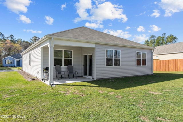 back of property with a yard, a patio area, and fence