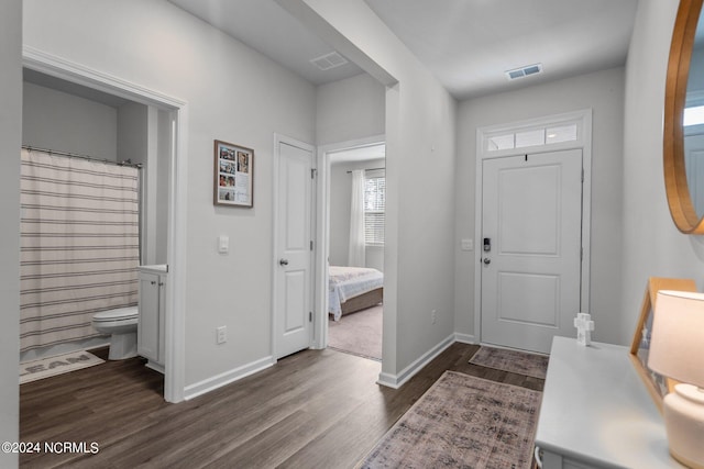 foyer entrance with dark wood-style floors, visible vents, and baseboards