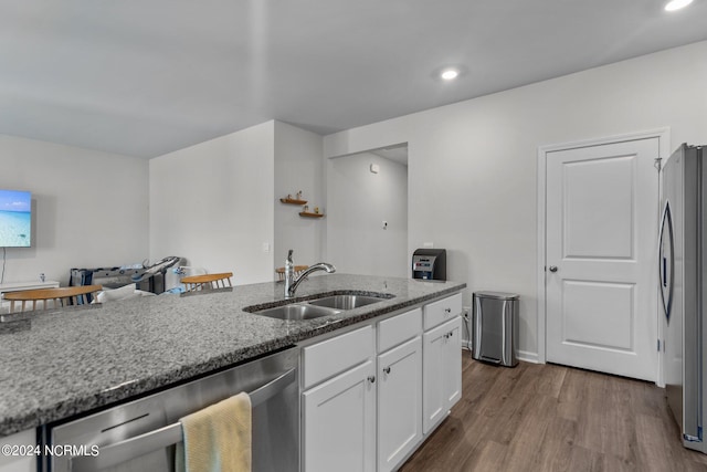 kitchen with dark wood-style floors, stainless steel appliances, stone countertops, white cabinets, and a sink