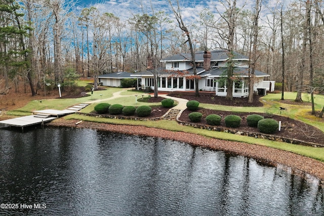 rear view of property featuring driveway, a water view, and a chimney