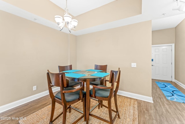 dining space with a notable chandelier, baseboards, and wood finished floors