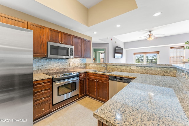 kitchen featuring tasteful backsplash, appliances with stainless steel finishes, light stone counters, a sink, and recessed lighting