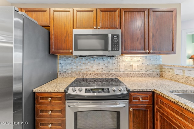 kitchen featuring light stone countertops, tasteful backsplash, and appliances with stainless steel finishes