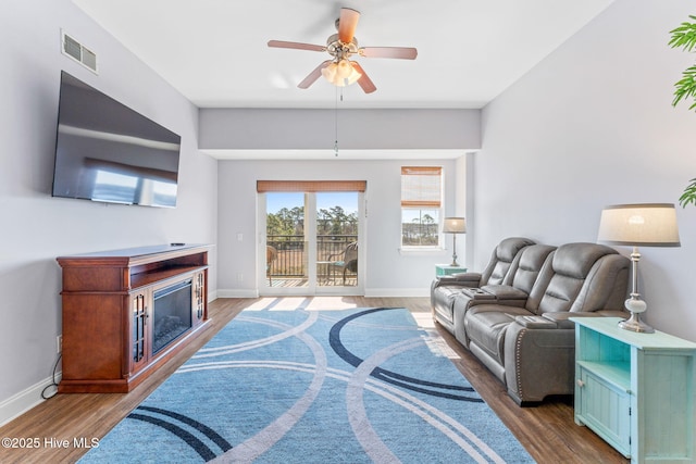 living area with baseboards, visible vents, ceiling fan, wood finished floors, and a fireplace