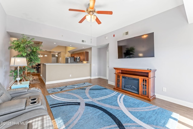 living area featuring baseboards, a fireplace, visible vents, and wood finished floors