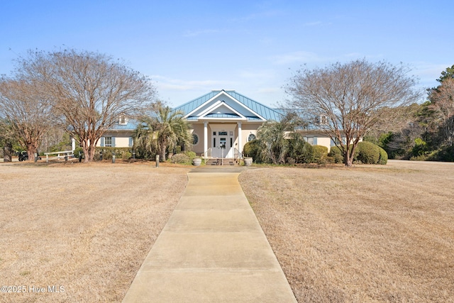 view of front facade featuring a standing seam roof, metal roof, and a front lawn