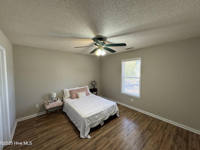 bedroom featuring dark wood-style floors, visible vents, a textured ceiling, and baseboards