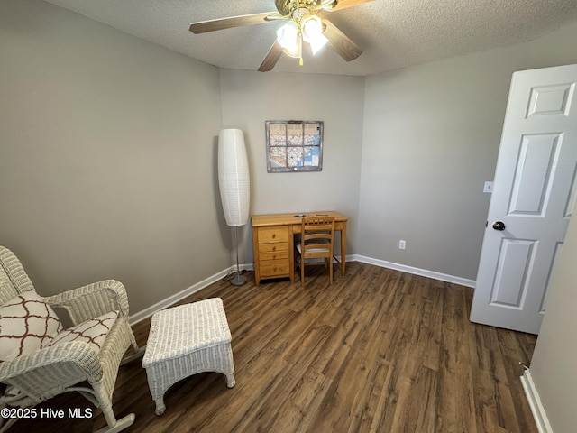 living area featuring dark wood-type flooring, a textured ceiling, and baseboards