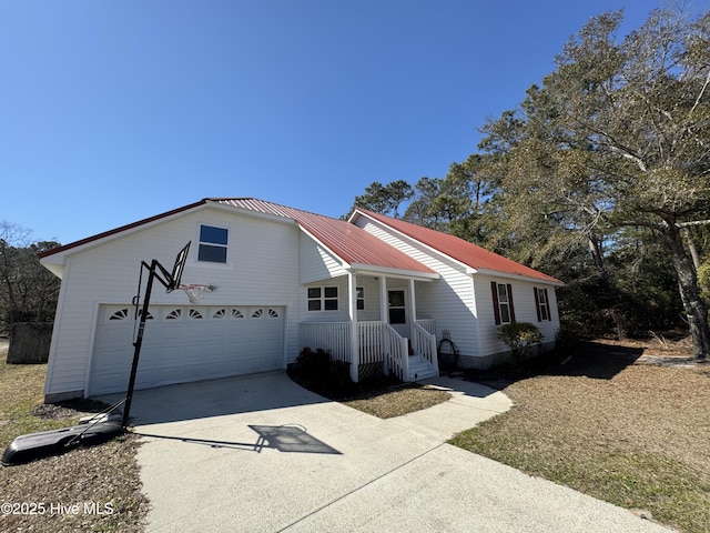 ranch-style home with driveway, a garage, and metal roof