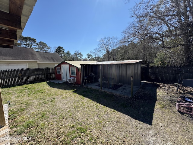 view of yard with a garage, a shed, a fenced backyard, and an outbuilding