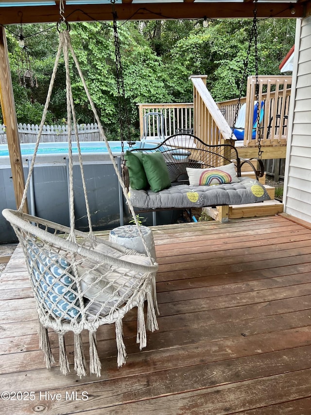 wooden terrace featuring an outdoor pool and fence